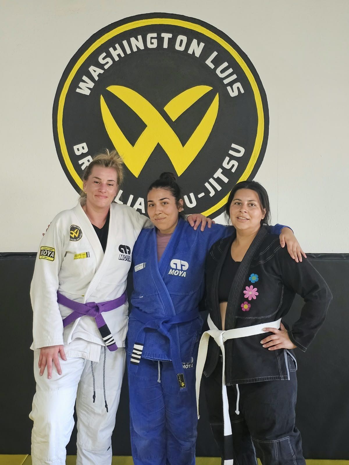 Three women in gis smiling together after Women Only Jiu Jitsu class at Washington Luis Brazilian Jiu-Jitsu
